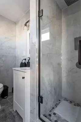 a bathroom with a shower with a glass door at The Modern Retreat 4BR 2BA Near NYC and Airport in Bayonne