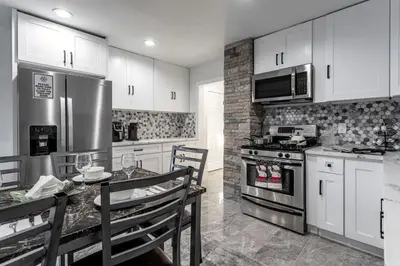 a kitchen with white cabinets and a stainless steel appliances at The Modern Retreat 4BR 2BA Near NYC and Airport in Bayonne