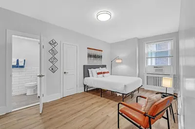 a white bedroom with a bed and a chair at Fairfax Apartments 303 Spacious 1 Bed 1 Bth in Philadelphia