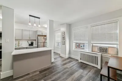 a kitchen with white walls and wooden floors and windows at Fairfax Apartments 303 Spacious 1 Bed 1 Bth in Philadelphia
