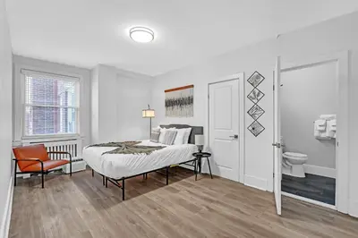 a white bedroom with a bed and a chair at Fairfax Apartments 603 Spacious 1 Bed 1 Bth in Philadelphia