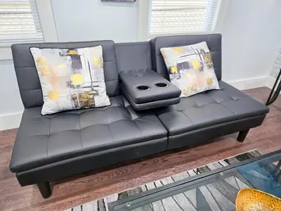 a black leather couch with a cell phone on it at Cozy apartment near New York City in Jersey City