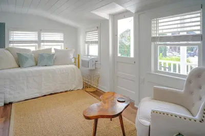 a white bedroom with a bed and a chair at Stylish Apt Walk to Shops, Dining, and Bucknell in Lewisburg