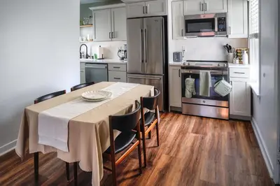 a kitchen with a table with chairs and a refrigerator at Stylish Apt Walk to Shops, Dining, and Bucknell in Lewisburg