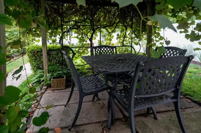 a black table and chairs sitting under a pergola at Garden Retreat Steps from Downtown Lewisburg in Lewisburg