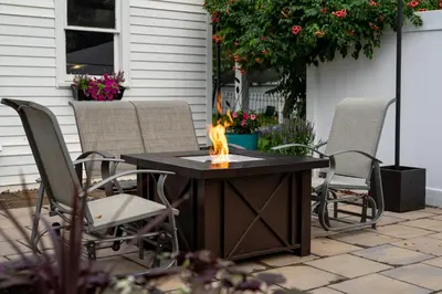 a fire pit sitting on a patio with chairs at Garden Retreat Steps from Downtown Lewisburg in Lewisburg