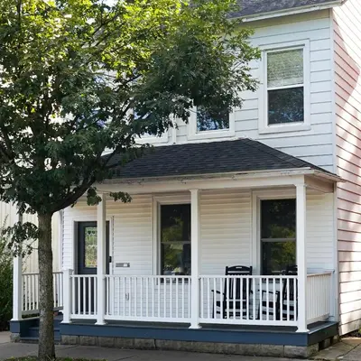 a screened in porch on a white house at Garden Retreat Steps from Downtown Lewisburg in Lewisburg
