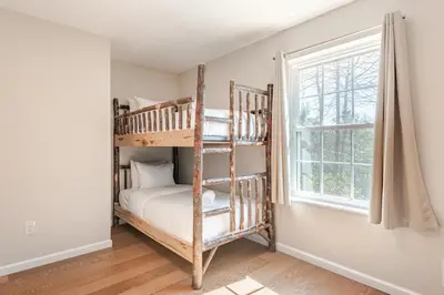 a bedroom with two bunk beds and a window at The Hangout Haven - Theater, Hot tub, Pickleball, Ping pong, Firepit in Long Pond