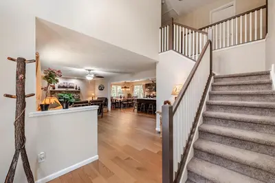 a staircase in a home with white walls and wooden floors at The Hangout Haven - Theater, Hot tub, Pickleball, Ping pong, Firepit in Long Pond