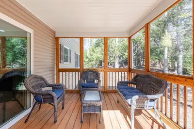 a screened in porch with wicker chairs and windows at The Hangout Haven - Theater, Hot tub, Pickleball, Ping pong, Firepit in Long Pond