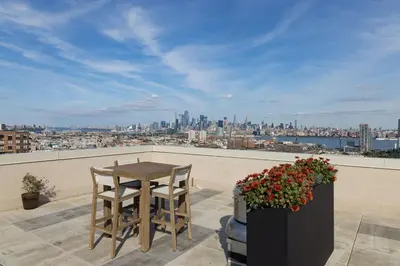 a table and two chairs on a balcony with a view at Chique Loft 10 Min from NYC with Gym, Pool & Sauna in Jersey City