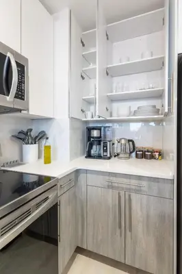 a kitchen with white cabinets and stainless steel appliances at Chique Loft 10 Min from NYC with Gym, Pool & Sauna in Jersey City