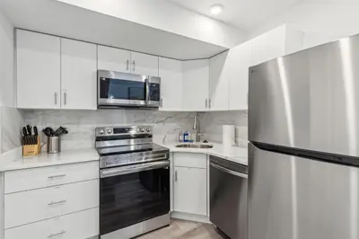 a kitchen with white cabinets and a stainless steel refrigerator at Stay at Luna on 800 Callowhill in Philadelphia