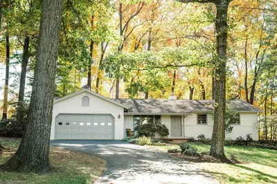 a white house with a garage in the woods at Wooded Cottage in Elizabethtown with hot tub and sauna in Elizabethtown