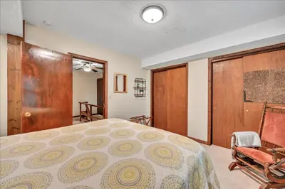 a bedroom with a bed and two chairs and a door at Swiss Chalet in Mount Gretna