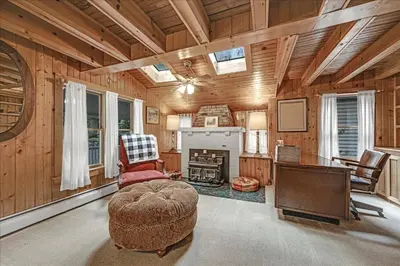 a living room with a fireplace and a chair and a table at Muhlenberg Cottage in Mount Gretna