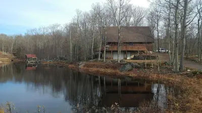a log cabin next to a river in the woods at Pocono Mountain Retreat in Cresco