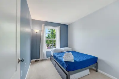 a blue bedroom with a bed and a window at Chic Modern Townhouse 4BR 4B in Wilmington