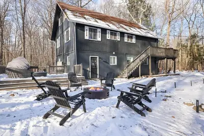 a black house with a fire pit in the snow at Cabin in the Woods in Wagners Forest Park