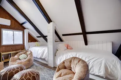 a attic bedroom with two beds and two chairs at Cabin in the Woods in Wagners Forest Park