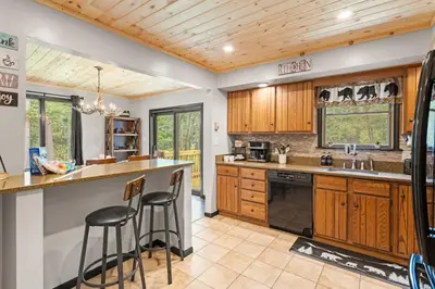 a kitchen with wooden cabinets and black appliances at Lazy Bear Retreat Outdoor Oasis Hot Tub etc in Blakeslee