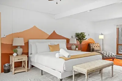 a bedroom with a white bed with an orange wall at Pocono Retreat Hot Tub MovieRoom GameRoom etc in Lake Harmony