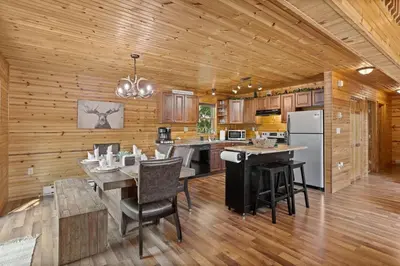 a kitchen with wooden walls and a table and chairs at Rustic Retreat - Fire-pit Hot-Tub and more in Albrightsville
