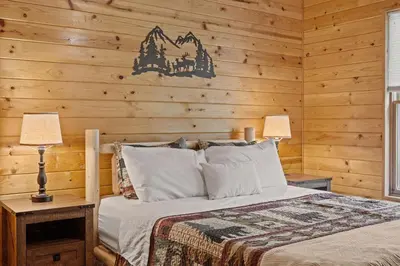 a bedroom with a bed and a wooden wall at Rustic Retreat - Fire-pit Hot-Tub and more in Albrightsville