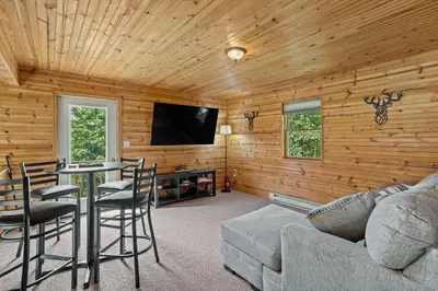 a living room with wooden walls and a flat screen tv at Rustic Retreat - Fire-pit Hot-Tub and more in Albrightsville