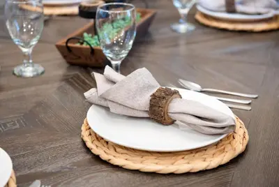 a table with a white plate on a wooden table with glasses at Cozy Cinema Cabin - Hot Tub and More in Blakeslee