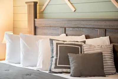 a bed with white pillows and a wooden headboard at Cozy Cinema Cabin - Hot Tub and More in Blakeslee