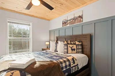 a bedroom with a bed and a wooden ceiling at Cozy Cinema Cabin - Hot Tub and More in Blakeslee