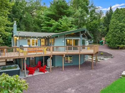 a house with a large deck and red chairs at The Lazy Bear Cabin Dome Hot Tub Sauna & More in Albrightsville