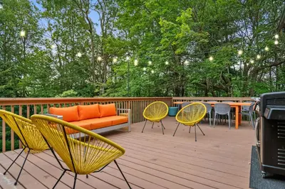 a deck with chairs and a couch and a table at The Lazy Bear Cabin Dome Hot Tub Sauna & More in Albrightsville