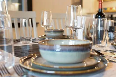 a table with plates and glasses and a bowl on it at The Lazy Bear Cabin Dome Hot Tub Sauna & More in Albrightsville