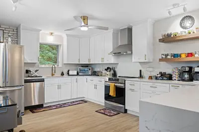 a white kitchen with white cabinets and stainless steel appliances at The Lazy Bear Cabin Dome Hot Tub Sauna & More in Albrightsville
