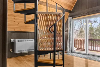 a spiral staircase in a room with a balcony at Whispering Pines - Lake Access Hot Tub Fire Pit in Blakeslee