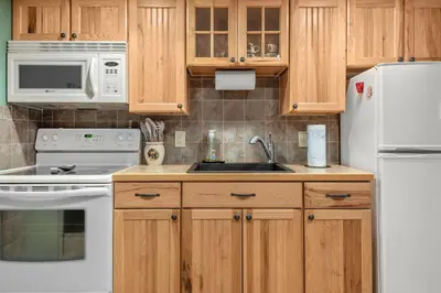 a kitchen with white appliances and wooden cabinets at Whispering Pines - Lake Access Hot Tub Fire Pit in Blakeslee