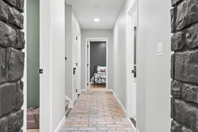 a hallway with white walls and a brick wall at NewReno 8BR 6BTH DECK GAMES PETS in Lake Harmony
