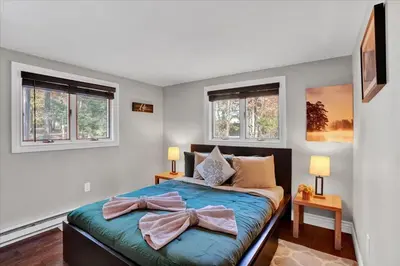 a bedroom with a bed with two windows at Serene Pocono Escape Hot Tub Lake Access in Albrightsville