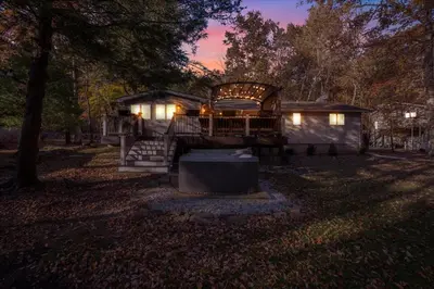 a cabin in the woods at night with lights at Serene Pocono Escape Hot Tub Lake Access in Albrightsville
