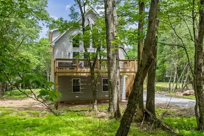 a house with a deck in the woods at Twin Chalet 6 BDs Hot Tub Game Area and more in Albrightsville