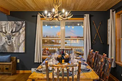 a dining room with a table with chairs and a chandelier at Lakefront Movie & Game Rooms Hot Tub Sauna etc in Albrightsville