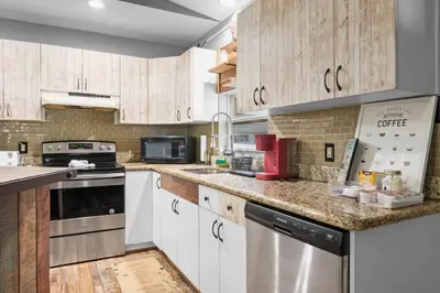 a kitchen with white cabinets and stainless steel appliances at Cabin Oasis - Nestled in the Woods Seclusion in Blakeslee