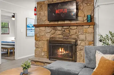 a living room with a stone fireplace with a television at Cabin in the Skye - 5 BDs Lake Harmony in Lake Harmony