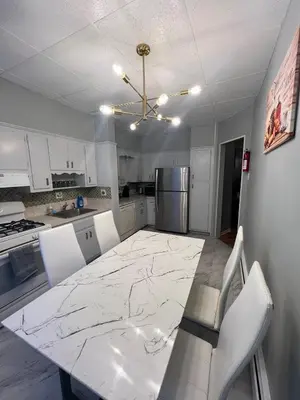 a kitchen with a large marble table and white chairs at Waterfront 4BR apt - 15Min to MetLife and TIMES SQ in Union City