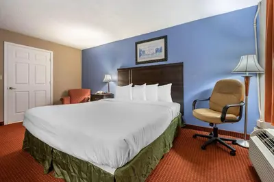 a hotel room with a large bed and a chair at Dutchland Motel in Lancaster