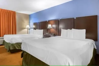 two beds in a hotel room with white sheets at Dutchland Motel in Lancaster
