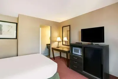 a hotel room with a bed and a flat screen tv at Dutchland Motel in Lancaster