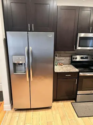 a stainless steel refrigerator in a kitchen with wooden cabinets at 18stStays in Philadelphia